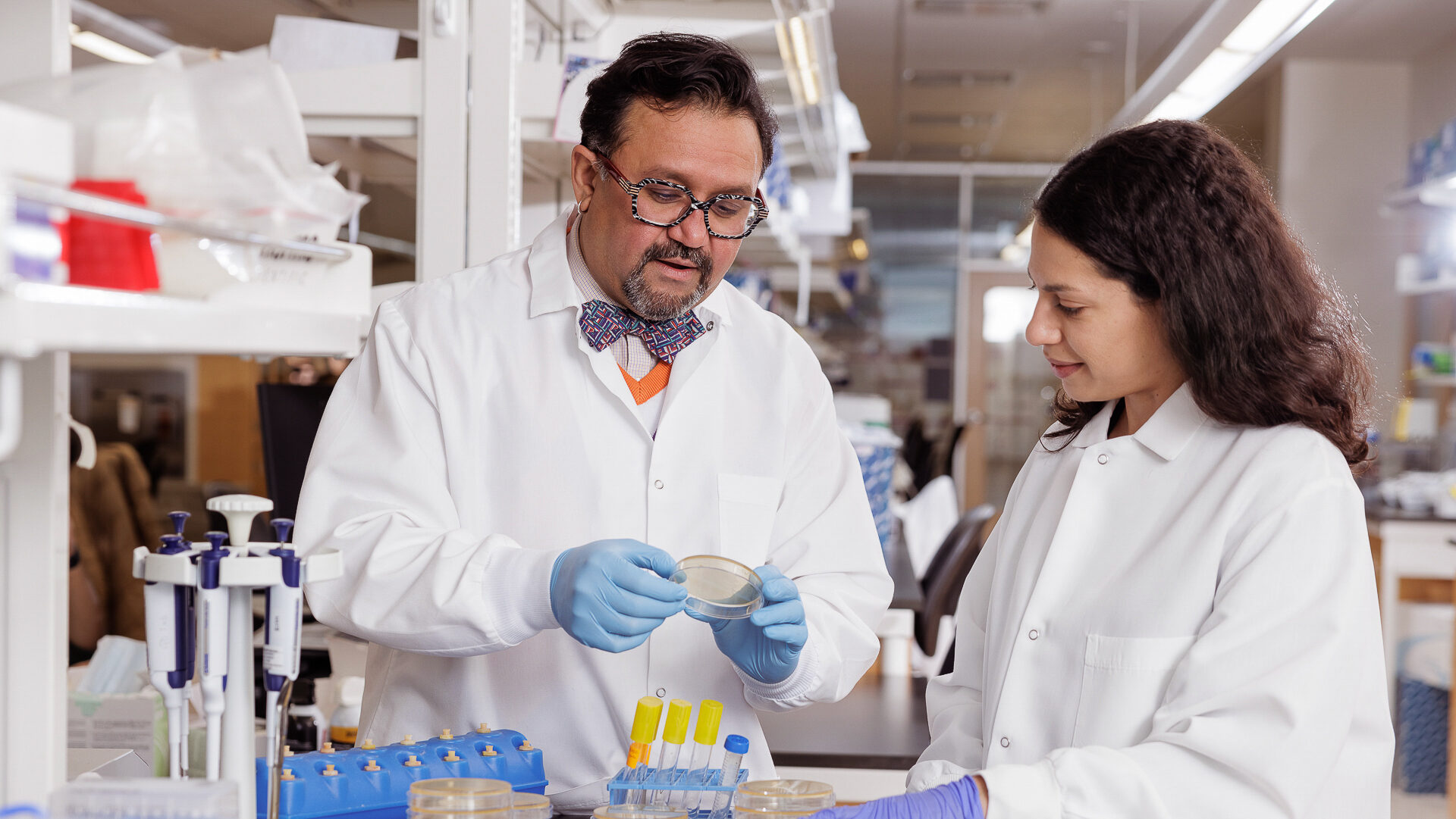 Gautam Dantas and Aura Ferreiro observe a petri dish in a research lab