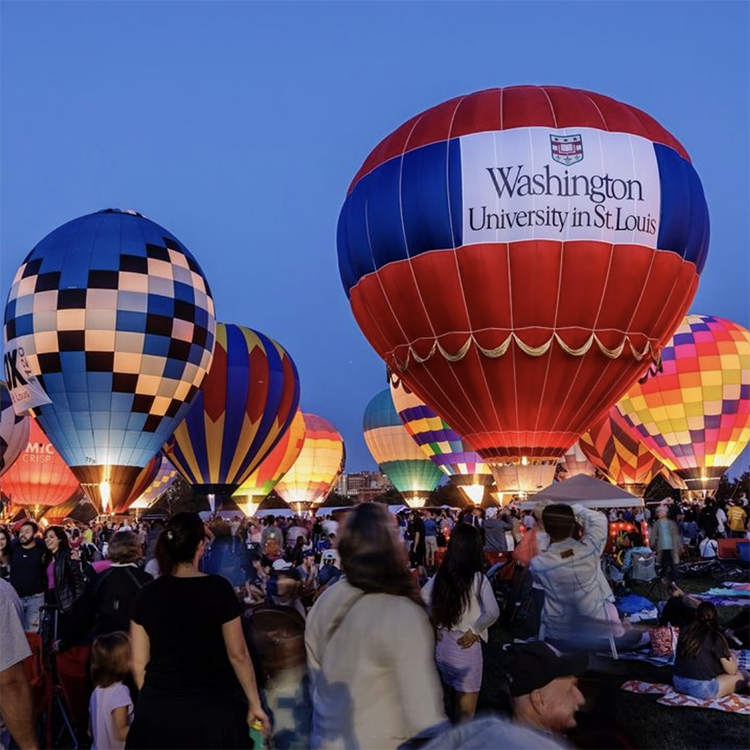 hot air balloons lit up among a crowd